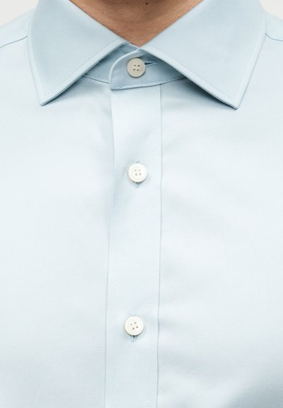 Φωτεινό γαλάζιο πουκάμισο με κουμπιά, με εμφανές γιακά και τρία λευκά κουμπιά στο μπροστινό μέρος.