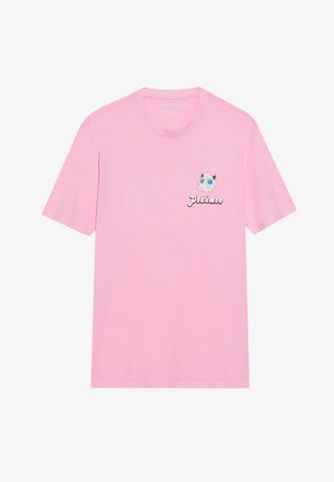 T-shirt rosa chiaro in cotone, con un piccolo personaggio Jigglypuff stampato e la parola "Pokémon" in testo bianco sul lato sinistro del petto.