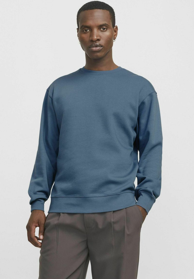 Sudadera azul para hombres con cuello redondo, mangas largas, puños y dobladillo de canalé, hecha de una tela suave y lisa. Diseño minimalista.