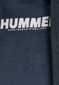 Mörkblå sweatshirt med tydlig vit text "HUMMER" och "SPORTSWEAR SINCE 1923" nedanför; texturerad tyg med ribbat krage.