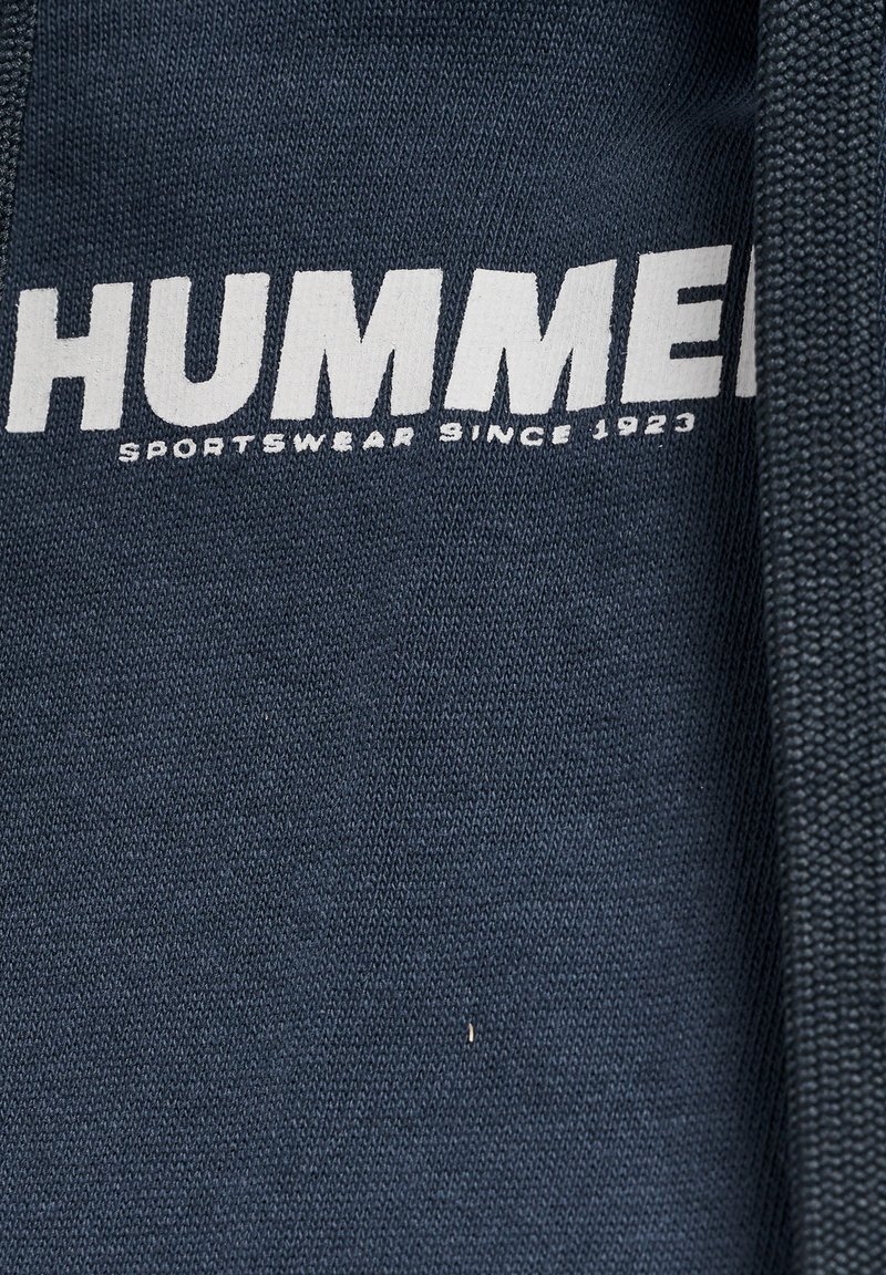 Granatowa bluza z wyraźnym białym napisem "HUMMER" z napisem "SPORTSWEAR SINCE 1923" poniżej; teksturowany materiał z prążkowanym kołnierzem.