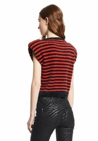 Rood en zwart gestreept cropped sweater met een fuzzy textuur en korte mouwen, gecombineerd met zwarte broeken met een subtiele gestreepte patroon.