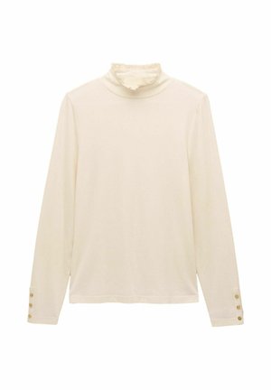 Crème lange mouwtop met gerimpelde hoge kraag en drie kleine gouden knopen op elke manchette, plat gelegd op een witte achtergrond.