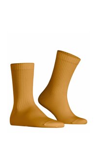 Calze a costine giallo senape con una texture liscia, alte fino al ginocchio e con una punta arrotondata. Presentano un aspetto semplice e classico.