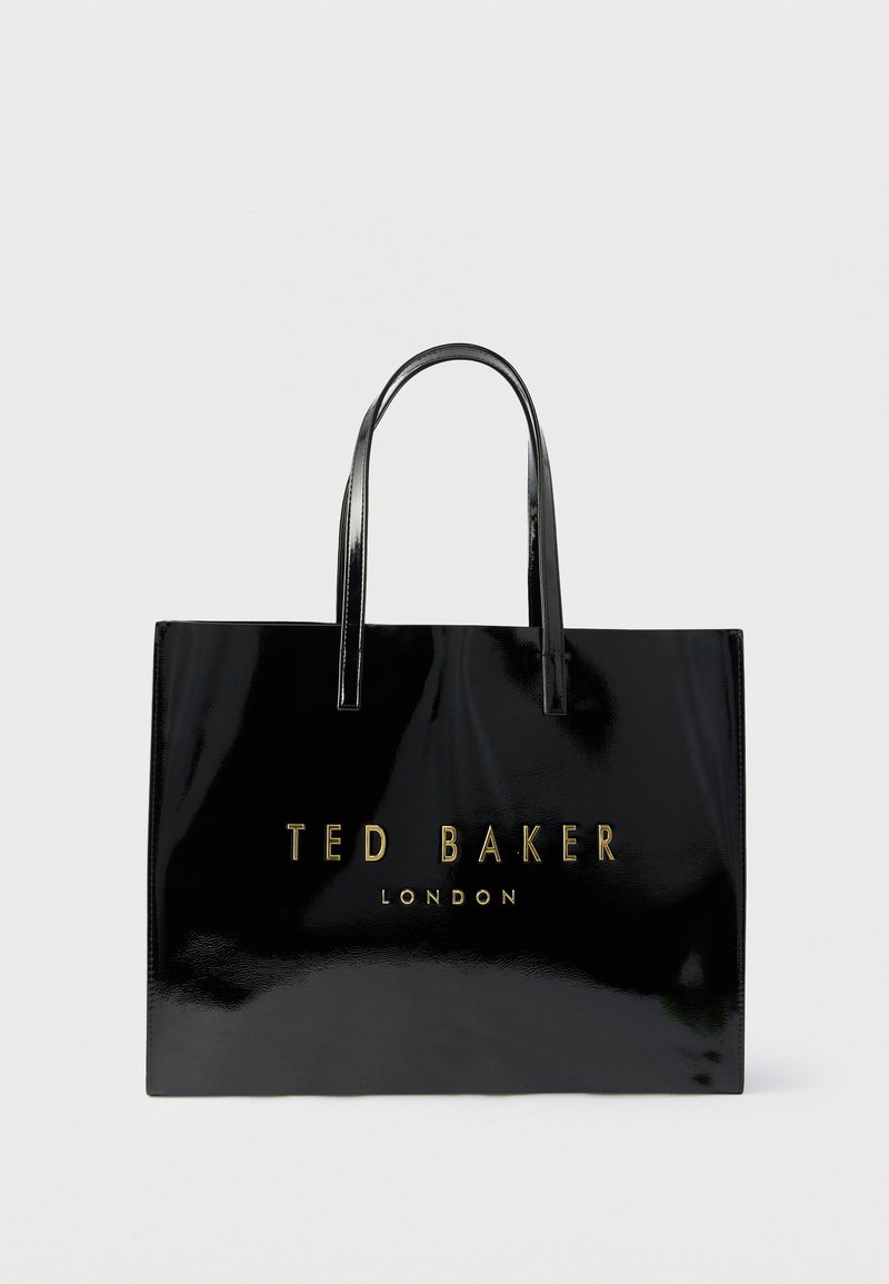 Svart skinnveske i lakkskinn med to håndtak, med preget gulltekst "TED BAKER LONDON" foran. Jevn overflate.
