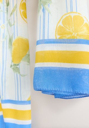 Pamučna tkanina s uzorkom limuna i lišća, s plavo-žutim horizontalnim prugama. Rubovi su obrubljeni ravnim šavom.