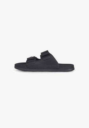 Zwarte open-teen slidesandaal met twee verstelbare klittenbandriemen en een platte zool, zijaanzicht op een witte achtergrond.