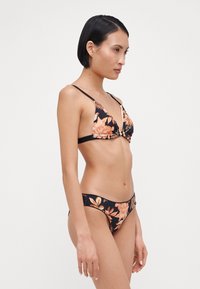 Črn cvetlični bikini s trikotnim vrhom z oranžnimi cvetovi, tankimi naramnicami in ujemajočimi se nizkimi hlačkami s teksturiranimi detajli.