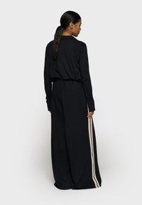 Zwart langwerpig jurkje met een losse fit, met een cinched taille en zijstrepen in een contrasterende kleur. Zachte stof, minimalistisch ontwerp.