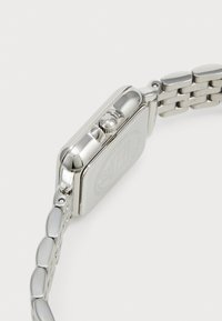 Silbernes Metall-Armbanduhr mit rechteckigem Gehäuse, strukturiertem Kranz und Gliederarmband. Die Rückseite hat ein graviertes Logo und eine glatte Oberfläche.