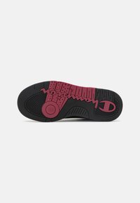 Suela de goma negra y burdeos con patrones texturizados, acento circular y detalle de logo. Incluye un diseño de banda de rodadura en zigzag para mejorar la tracción.