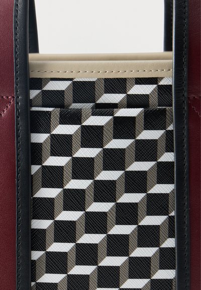 Κοντινό πλάνο τμήματος τσάντας με γεωμετρικό μοτίβο κύβων σε μαύρο, λευκό και γκρι, περιτριγυρισμένο από μαύρο και μπορντό δερμάτινο φινίρισμα.