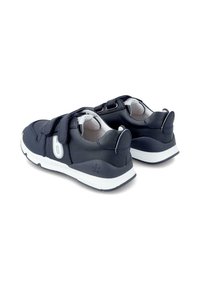 Zapatillas de cuero azul marino con suelas blancas, que cuentan con una correa de velcro, un interior suave y bordes redondeados en los talones.