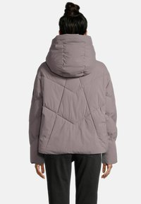 Steppjacke in hellem Mauve mit hohem Kragen und Kapuze. Verfügt über gesteppte geometrische Muster und elastische Bündchen für zusätzliche Wärme.