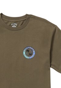 Camiseta de algodón verde oliva con un logo redondo e iridiscente que presenta palmeras y el texto "Billabong Desde 1973" en el pecho.