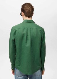 Groene langharige shirt met een zachte textuur, spitse kraag, plooi aan de achterkant en met knopen afgewerkte manchetten, gecombineerd met blauwe spijkerbroek, gezien vanuit de achterkant.