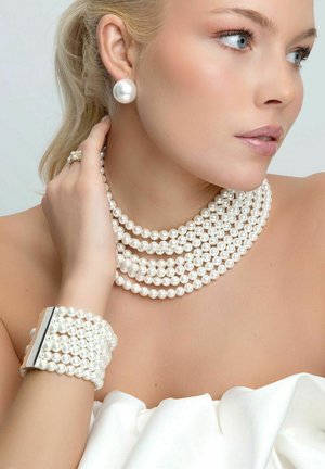 Pärlsmyckeset med flera strängar av vita pärlor, ett pärlarmband med silverdetaljer och stora pärlörhängen.