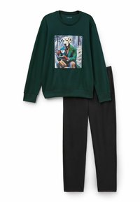 Groene sweatshirt met een geprint grafisch ontwerp van een hond in een pak die een drankje vasthoudt; gecombineerd met zwarte broek, beide gemaakt van een zachte stof.