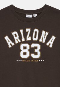 Mørk brun hettegenser med «ARIZONA 83» i fet hvit og gull skrift, med «COLLEGE LEAGUE» under og dekorative stjerner.