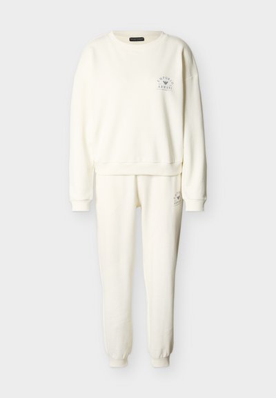 Σετ φούτερ και παντελόνι φόρμας σε κρεμ χρώμα με ριμπ μανσέτες και λογότυπα Emporio Armani στο στήθος και τον μηρό.