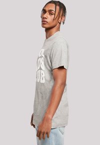 Grijze katoenen t-shirt met korte mouwen en een ronde hals. Voorzien van een vet wit opschrift "COOL KIDS CLUB" aan de voorkant. Klassieke pasvorm.