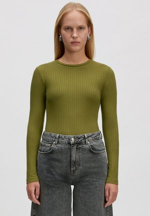 Olivenfarbener, gerippter Langarmtop, körperbetontes Design, runder Ausschnitt, kombiniert mit hochgeschnittenen, ausgewaschenen grauen Jeans.