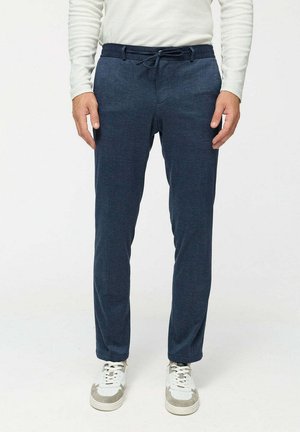 Marineblaue Hose aus strukturiertem Stoff, mit elastischem Bund und Kordelzug-Detail, kombiniert mit weißen Sneakers.
