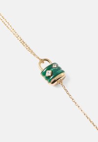 Colar de corrente dourada com um pendente em forma de fecho verde, decorado com três strass transparentes. O pendente possui uma superfície texturizada e um acabamento metálico.