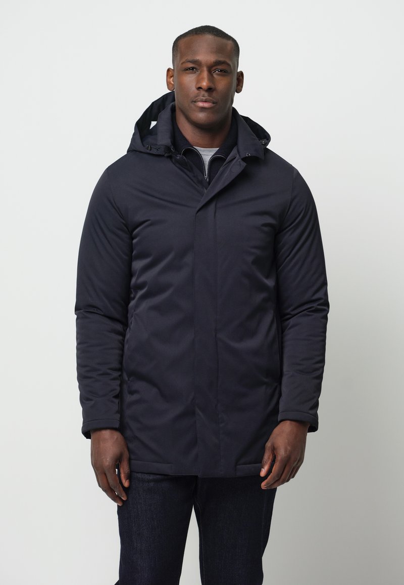 Granatowa, długosleeve kurtka z zapięciem na zamek z przodu, z przypiętym kapturem i bocznymi kieszeniami. Wykonana z gładkiego, wodoodpornego materiału.