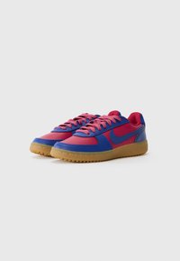 Plave i ružičaste tenisice s glatkim kožnim gornjim dijelom, gumenom potplatom i usklađenim vezicama. Imaju swoosh logo sa strane. Klasičan dizajn niske verzije.