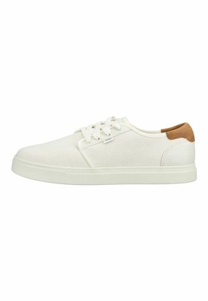 Witte lage canvas sneaker met witte veters, rubberen zool en een bruine suède patch op de hiel.