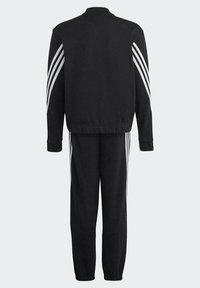 Completo in tuta nera con giacca con zip e pantaloni affusolati, con accentuazioni a tre strisce bianche lungo le maniche e i lati. Tessuto morbido.