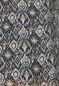 Tissu à motifs avec un fond noir orné de dessins géométriques et floraux complexes en beige, tan et blanc. Tissage texturé visible.