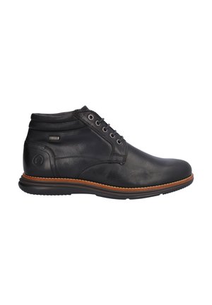 Bota de piel negra hasta el tobillo con cierre de cordones en la parte delantera, cuello acolchado, ribete marrón a lo largo de la suela y logo en relieve en la zona del talón.