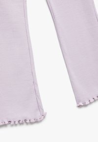 Tessuto lilla a coste con bordi sfilacciati, che forma un design ampio e morbido. Presenta una superficie testurizzata e fessure laterali per un tocco di dettaglio in più.