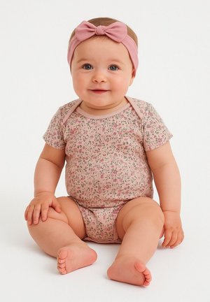 Une combinaison à motifs floraux roses avec des manches courtes, en matériau doux, et un bandeau assorti rose avec un nœud. Posé sur un fond blanc.