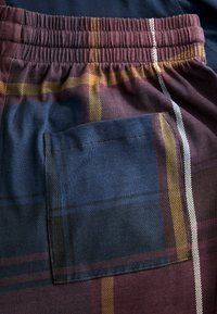 Karierte Shorts in Marineblau, Bordeauxrot und Gold. Mit einem elastischen Bund und einer Paspeltasche. Weiche Textur mit einer glatten Oberfläche.