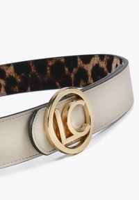 Beige läderbälte med en slät yta, med en guldfärgad cirkulär spänne med "LC"-logotyp och en leopardmönstrad inredning.