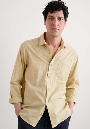 Lichtgele, lange mouw shirt met een gestructureerde stof, knoopsluiting aan de voorkant en een enkele borstzak. Mouwen opgerold bij de polsen.