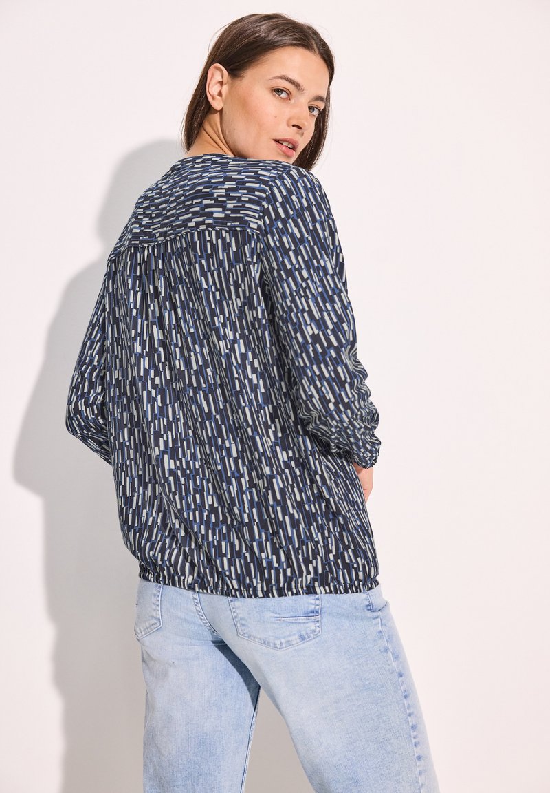 Blusa a maniche lunghe blu navy con motivo, caratterizzata da un design astratto in azzurro chiaro e bianco. L'orlo elastico in vita migliora la vestibilità.