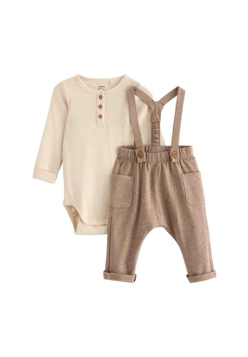 Krémový bodysuit s dlouhým rukávem a třemi knoflíkovými průramky, doplněný hnědými laclovými kalhotami s ohrnutými manžetami a předními kapsami.