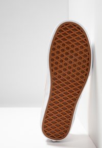 Podeszwa buta z pomarańczową, teksturowaną powierzchni�ą gumową, geometrycznym wzorem i białymi bokami, ukazująca trwałość i konstrukcję zapewniającą przyczepność.