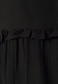 Tecido preto texturizado com linhas verticais; apresenta um acabamento em babados. O material é suave e leve, proporcionando uma aparência fluida.