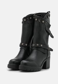 Czarne skórzane botki za kostkę z masywnym obcasem, regulowanymi paskami i ćwiekowanymi detalami na cholewce oraz teksturowaną podeszwą.