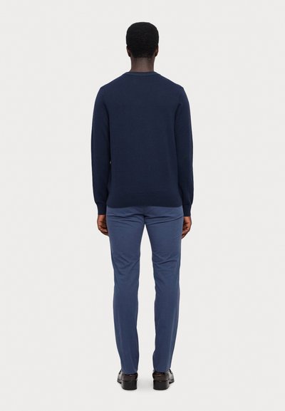 Navy sweater with long sleeves and a crew neckline, paired with light blue trousers. Smooth fabric, fitted design, and ribbed cuffs.