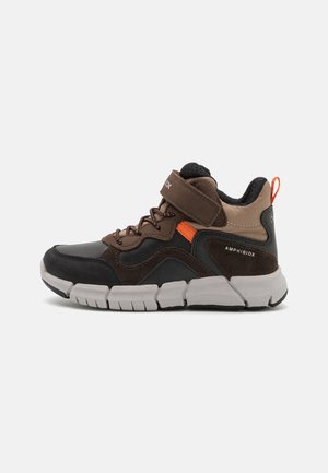 Braun und schwarze mid-top Schuhe aus synthetischen und Wildledermaterialien, ausgestattet mit einem Klettverschluss, strukturierten Sohlen und orangefarbenen Akzenten.