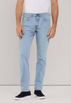 Lichtblauwe denim jeans met een rechte pasvorm, vijf zakken en een knoopsluiting. Voorzien van subtiele vervaging en gecombineerd met donkere sneakers.