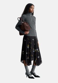 Dark gray ribbed sweater with a zip, black floral-patterned midi skirt, gray knee-high socks, and black pointed-toe heels. Brown handbag.