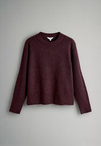 Vínový svetr s kulatým výstřihem, dlouhými rukávy a měkkým, strukturovaným úpletovým materiálem. Má volnější střih a lem sahající k pasu.