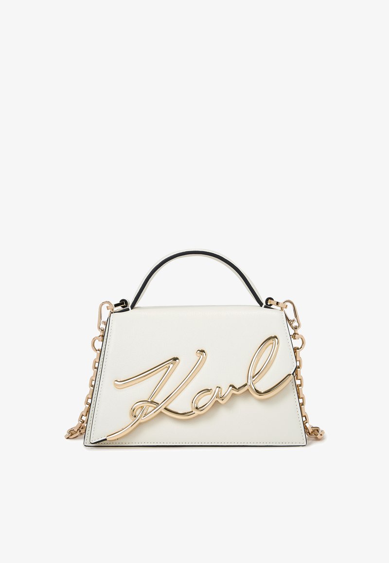 White leather handbag with a structured design, featuring a gold metallic signature detail, black trim, and a chain strap.